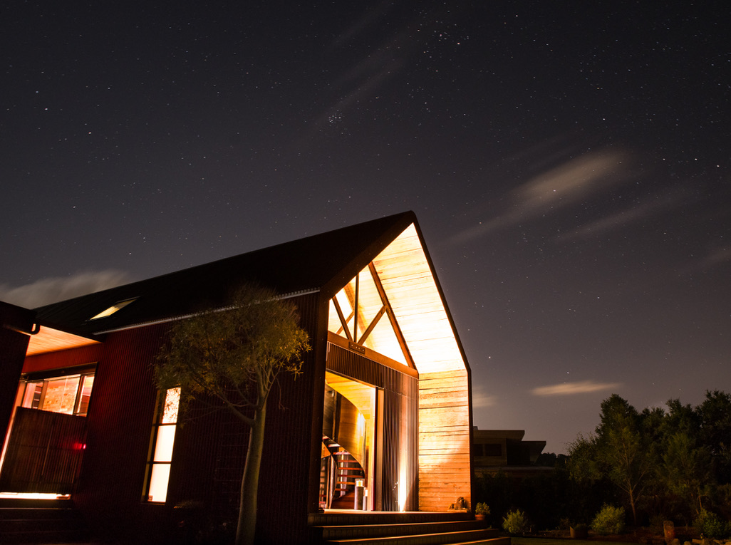 Lakeview at night, with an illuminated timber-lined gable and dark exterior cladding.