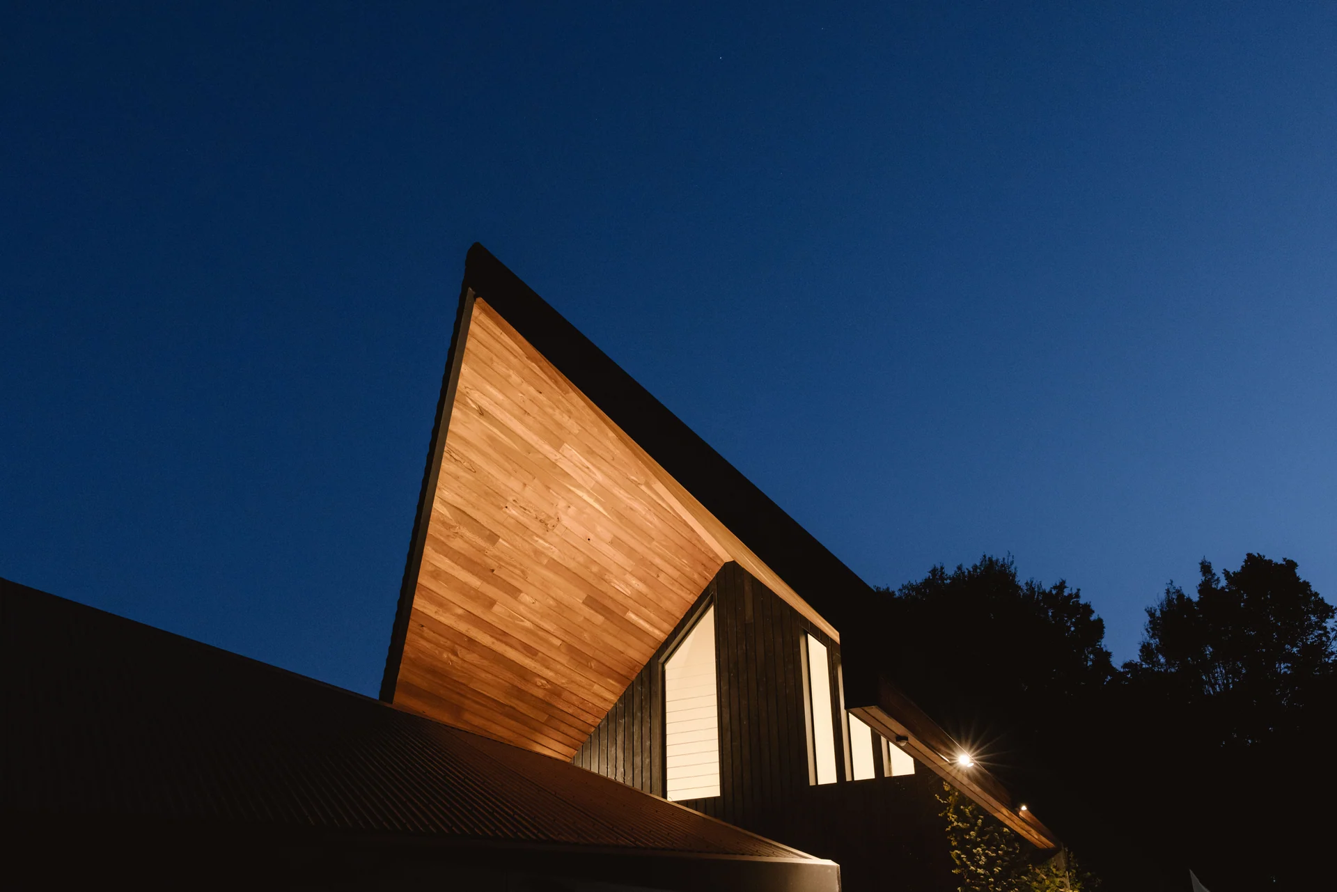 Illuminated timber-lined gable and dark exterior cladding at Warri Way.